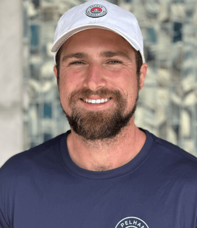 Pelham Racquet Club tennis pro Matheus Chain wears a blue t-shirt and white cap with the PRC logo.